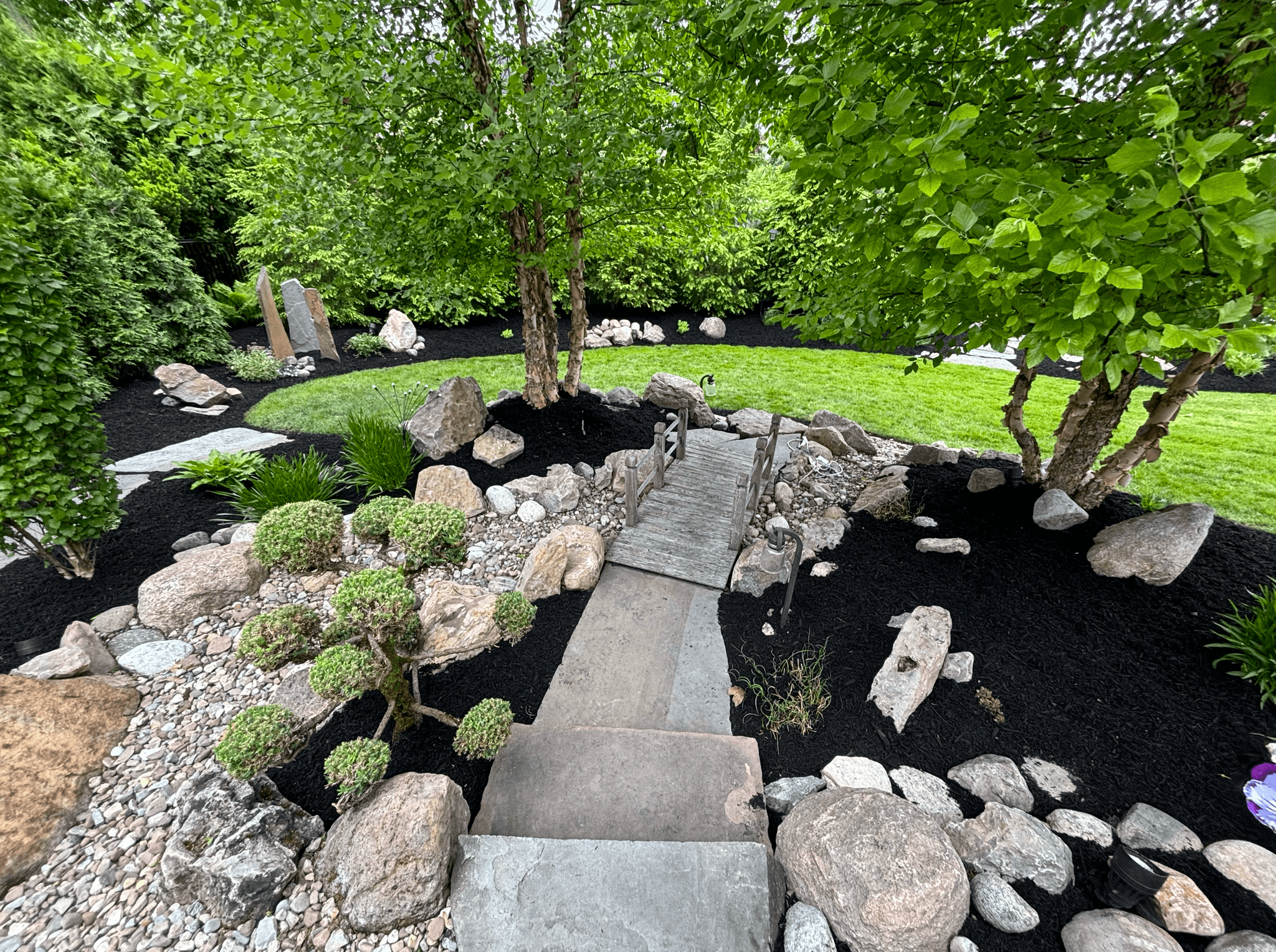 Professional landscaping with wooden bridge and garden design