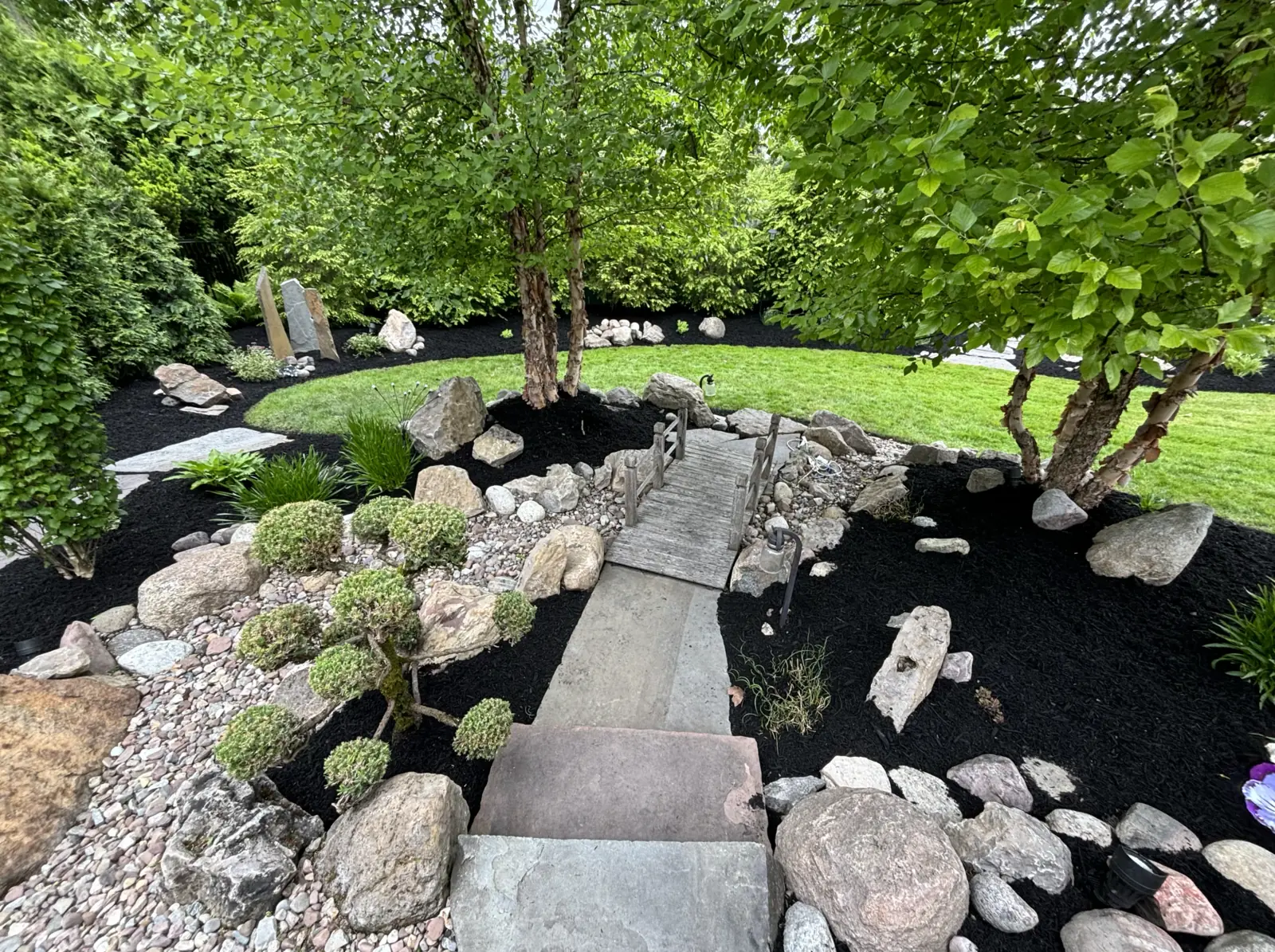 Professional landscaping with wooden bridge and garden design