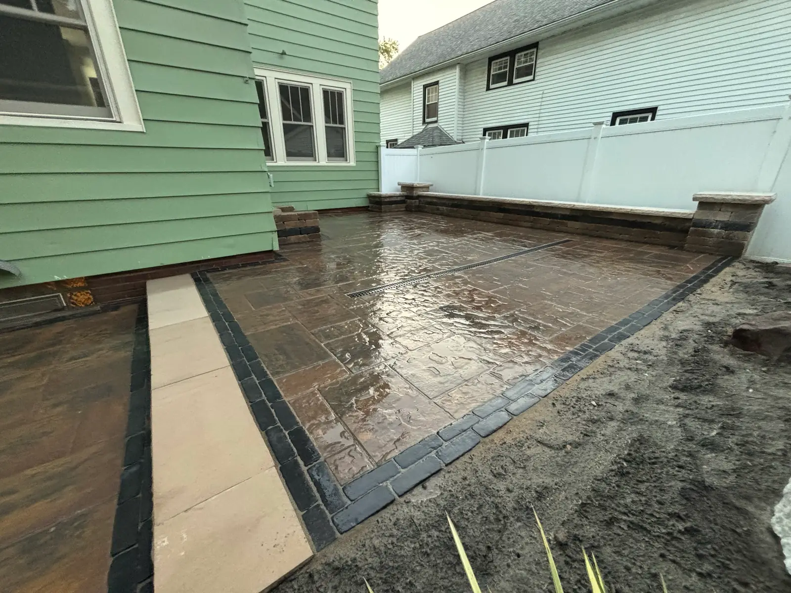 Close view of a stamped-concrete patio with contrasting border and drainage