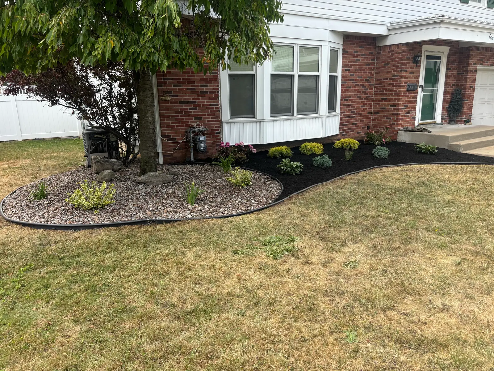 Finished front garden combining decorative stone and a dark mulch bed